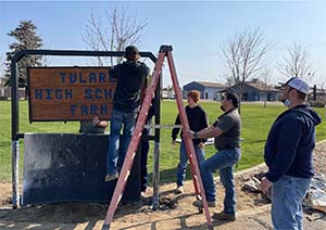 Students hanging Tulare High School Farm sign